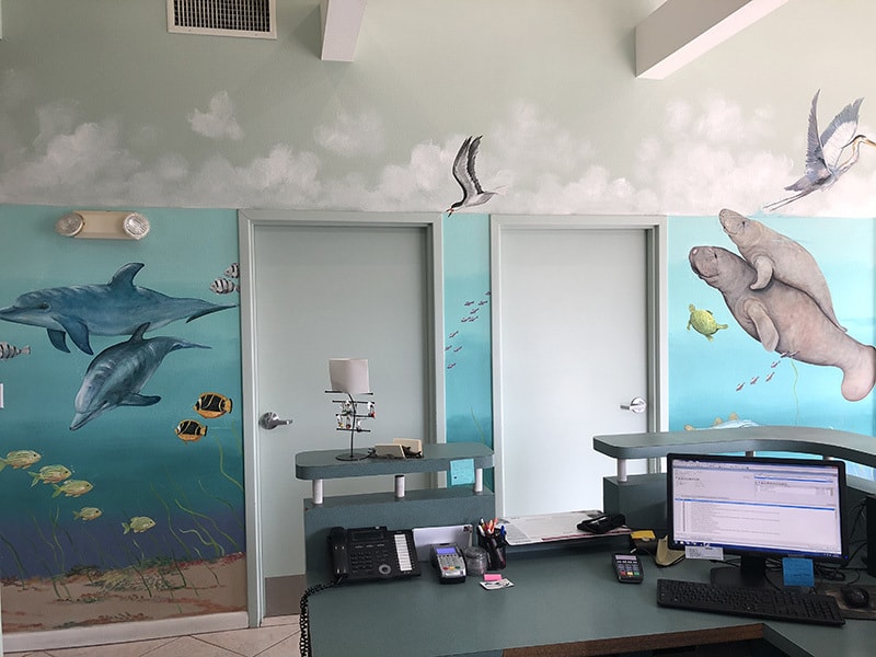 The mural inside Gulf Animal Hospital next to the reception desk and exam room doors. The mural is of different sea creatures and a few sea birds